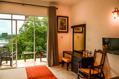 a living room with a desk and a large window at Agbo Hotel in Polonnaruwa