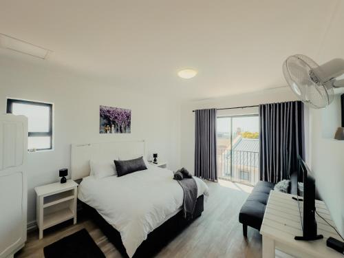 a white bedroom with a bed and a window at Gaiaqua Guesthouse in Gqeberha