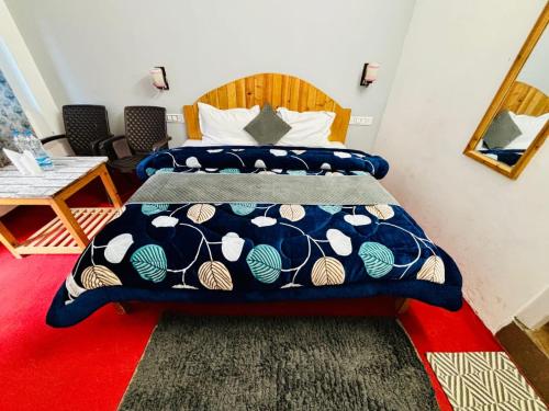a bedroom with a bed with a blue and white comforter at The Nature's Vault Jibhi in Kulu