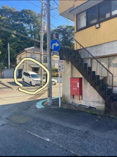 a arrow sign on a street next to a building at 一棟貸切ゲストハウス in Enoura