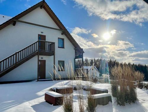a building in the snow with benches in front of it at Apartmány MAX in Vaclavov u Bruntalu