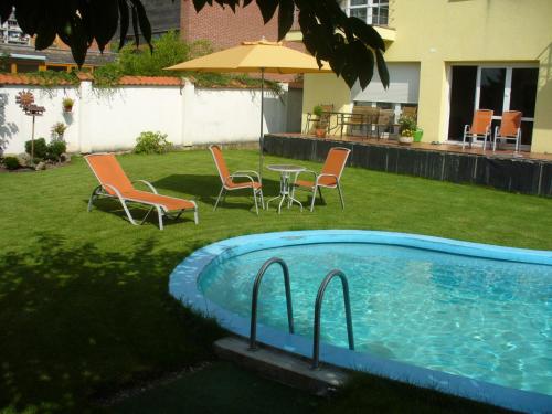 a pool with chairs and a table and an umbrella at Fontána in Prague