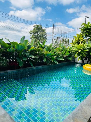 a swimming pool with blue tiles in a garden at Ban Chomchan Pool Villa Khaoyai in Ban Tha Chang
