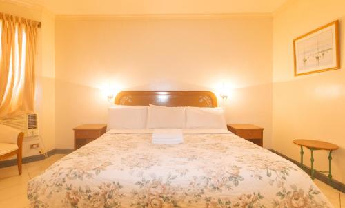 a bedroom with a bed with two tables and two lamps at Royal Am Rei Hotel by RedDoorz in Bacolod