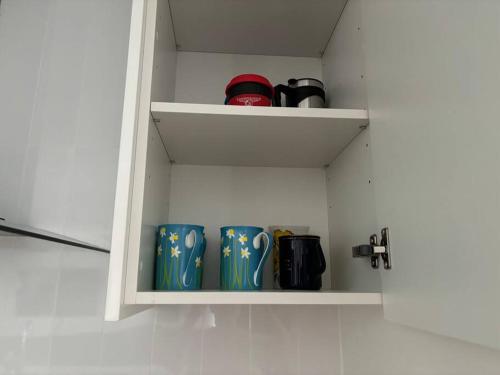 a cupboard with three blue mugs in it at Family size tropical oasis retreat netflix wifi in Redlynch