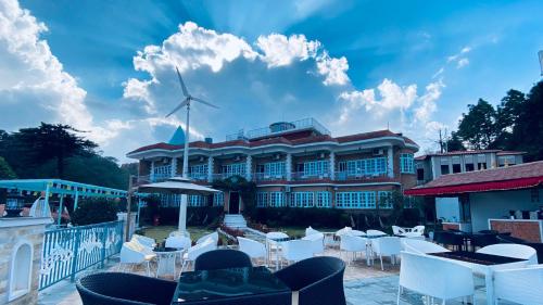 a building with white chairs and tables and a windmill at Mountain Vista Retreat in Nagarkot