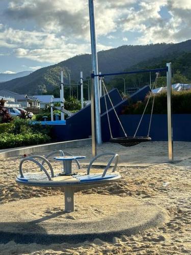 a surfboard on a stand in the sand near a playground at Family size tropical oasis retreat netflix wifi in Redlynch