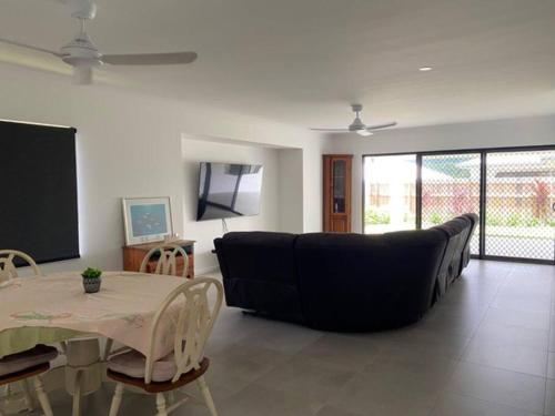 a living room with a black couch and a table at Family size tropical oasis retreat netflix wifi in Redlynch