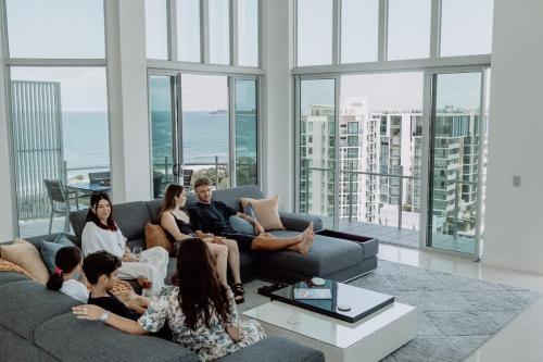 a group of people sitting on a couch in a living room at Aquavista Penthouse - Stunning 180 Views in Maroochydore