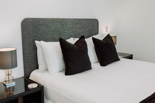 a bed with black and white pillows on it at Aquavista Penthouse - Stunning 180 Views in Maroochydore