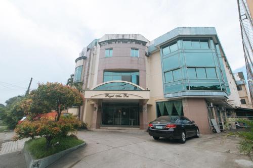 a building with a car parked in front of it at Royal Am Rei Hotel by RedDoorz in Bacolod