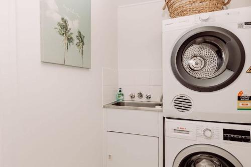a kitchen with a washing machine and a sink at Coastal Charm - Pet & family friendly in Marcoola