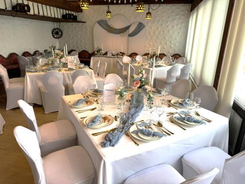 a room with white tables and white chairs and a table set up at Hotel Simonshof in Wolfsburg