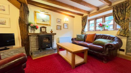 sala de estar con sofá de cuero y chimenea en Malston Mill Farm, en Kingsbridge