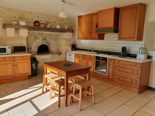 une cuisine avec des placards en bois, une table et une cheminée dans l'établissement Le logis de l'epinoux, à Jardres