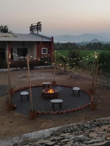 a fire pit with benches and lights in front of a house at Hotel Ekant tourist resort in Junnar