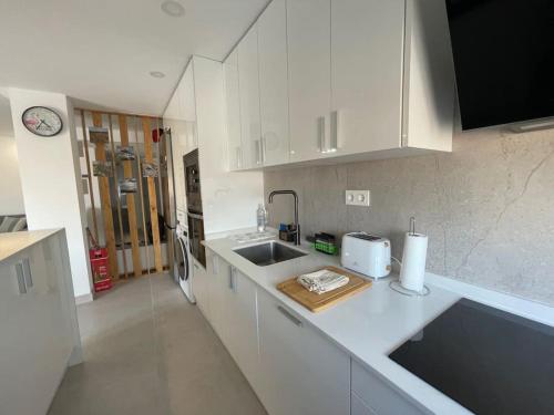 a white kitchen with a sink and a refrigerator at Cabosun in El Cabo de Gata