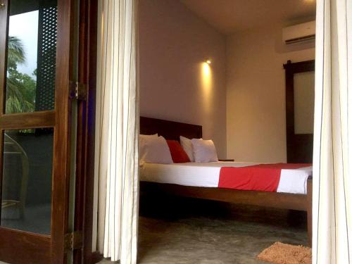 a bedroom with a bed with red and white sheets at Sithagi Villa Unawatuna in Unawatuna