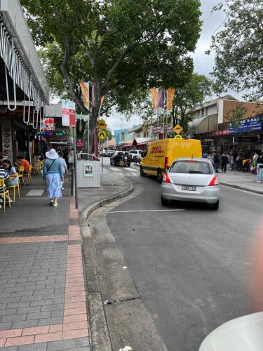 a woman walking down a city street with a yellow van at Alison's central apartment in Cabramatta
