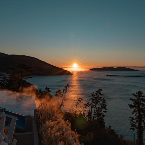 a sunset over a body of water with the sun setting at Hotel SANG SANG & Private SANG SANG POOL VILLA in Geoje 