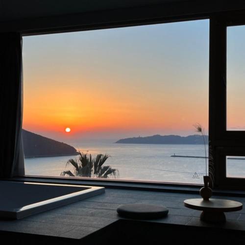 a view of a sunset from a room with a window at Hotel SANG SANG & Private SANG SANG POOL VILLA in Geoje 