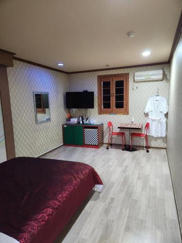 a bedroom with a bed and a table and a tv at Daebudo Hue Motel in Ansan