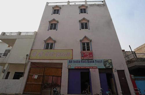 a tall white building with a sign in front of it at Super Hotel O Shree Shree Guest House in Varanasi