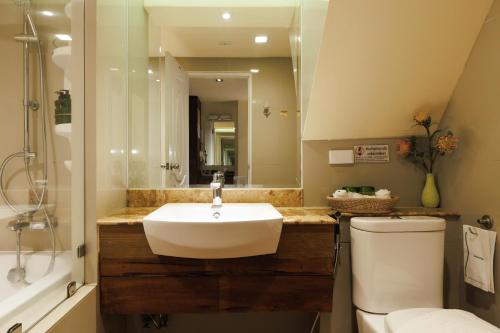 a bathroom with a sink and a toilet and a mirror at Le Charcoa Hotel in Chiang Mai