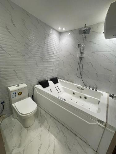 a white bathroom with a tub and a toilet at Al Somow Chalets in Dahaban