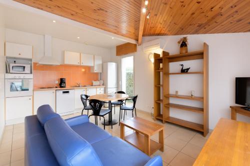 a living room with a blue couch and a table at Résidence Amaréna in Saint-Paul-lès-Dax