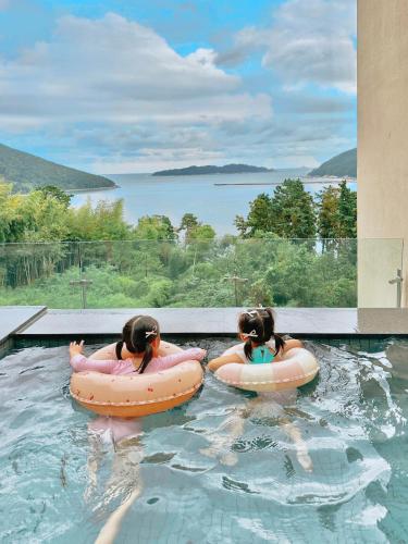 two girls riding on inflatables in a swimming pool at Hotel SANG SANG & Private SANG SANG POOL VILLA in Geoje 