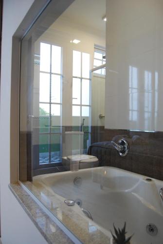 a bathroom with a bath tub with a large mirror at Pousada Bahia Pelô in Salvador