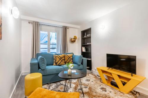 un salon avec un canapé bleu et une télévision dans l'établissement Sweett- Aboukir I, à Paris