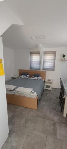 a bedroom with a large bed and two windows at Lebegő Falu Vendégház in Oroszlány