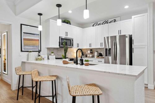 una cocina con armarios blancos y una gran isla con taburetes. en The Laurel Apartments in Chandler, en Chandler