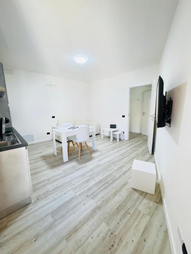 a kitchen and dining room with white furniture and wooden floors at Old Town Top Apartment Biella Centro in Biella
