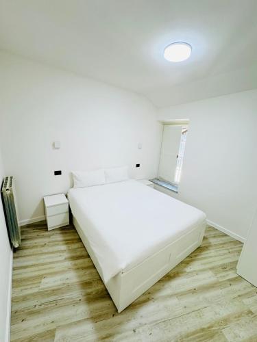 a white bed in a white room with wooden floors at Old Town Top Apartment Biella Centro in Biella