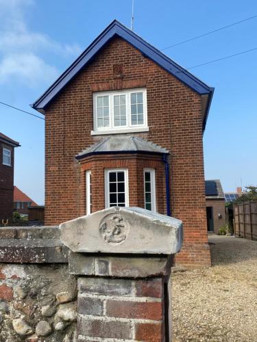 a brick house with a window on top of a brick wall at old coastguards station in Wells next the Sea