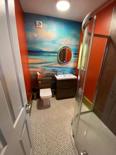 a bathroom with a painting of the ocean on the wall at old coastguards station in Wells next the Sea