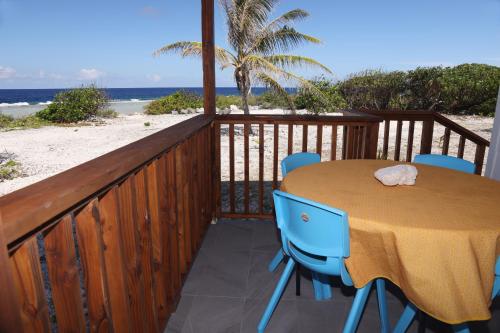a wooden deck with a table and chairs on the beach at Oteaeva Lodge - FAKARAVA in Rotoava