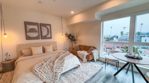 a bedroom with a bed and a table and a large window at Lovely Studio in heart of Hollywood in Los Angeles