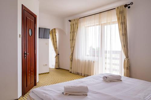 a bedroom with a bed and a large window at Q Resort and Spa in Săcele