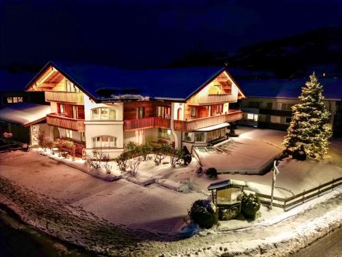 a large building with a christmas tree in the snow at VILLAWILLI - Gemütliche Ferienwohnungen in Fischen