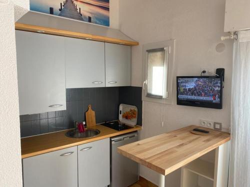 Il comprend une cuisine avec un évier et une télévision murale. dans l'établissement Résidence Euréka H137, au Cap d'Agde
