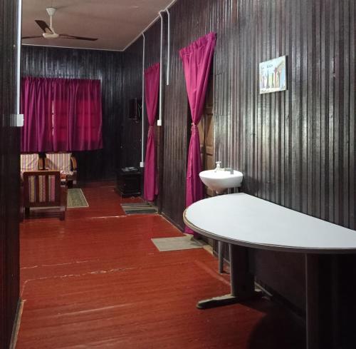 a bathroom with a table and a sink and pink curtains at Barokah Seaview Homestay, Bachok in Bachok