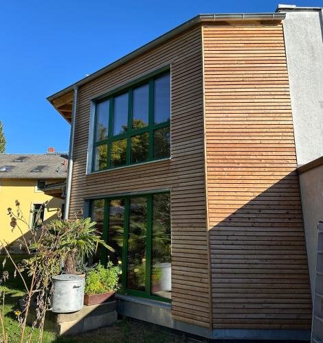 a house with wooden siding and large glass windows at Gartenhaus Luise in Dresden