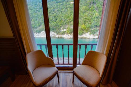 two chairs in front of a window with a view of the water at Hill River Hotel in Agva