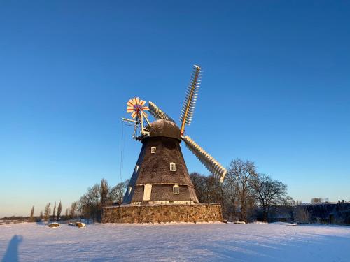 a windmill with a flag on it in the snow at GRUBBE MØLLE Bed & Breakfast in Fåborg