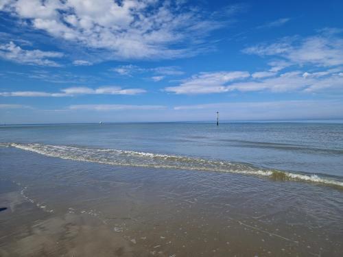 a beach with the ocean and a lighthouse in the distance at Oostduinkerke View in Oostduinkerke