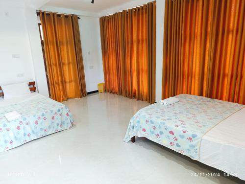 a bedroom with two beds and orange curtains at Aurora Echo Villa in Matara